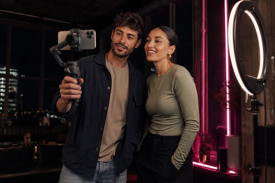 Two creators filming a collab video with a phone gimbal in a loft studio