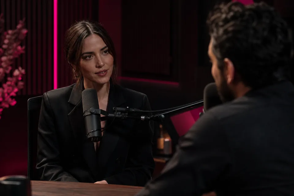 Performer being interviewed in a podcast studio with microphones